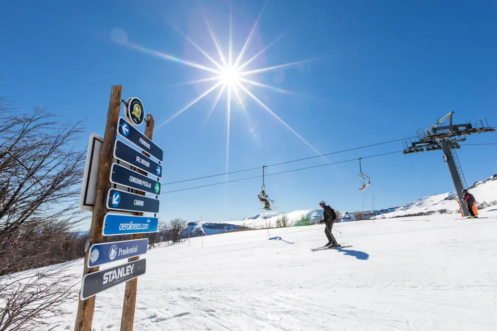 Skier casually passing signs in Chapelco