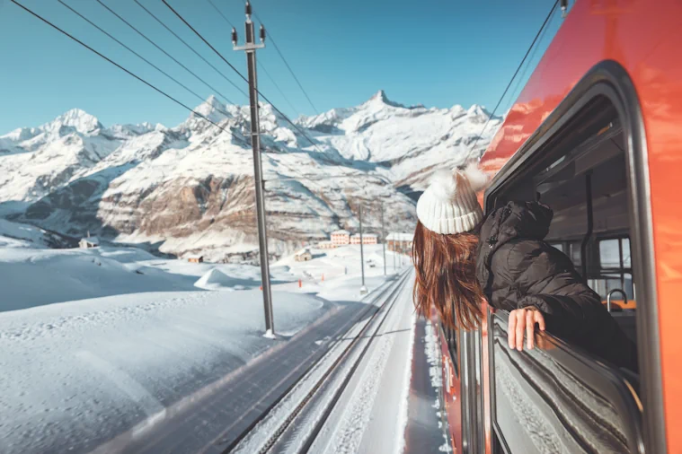Lady looking out the train window over the snowy mountains